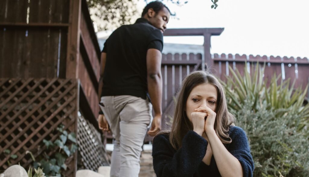 A distressed woman sitting as a man walks away, symbolizing how to let go of hurt and betrayal.