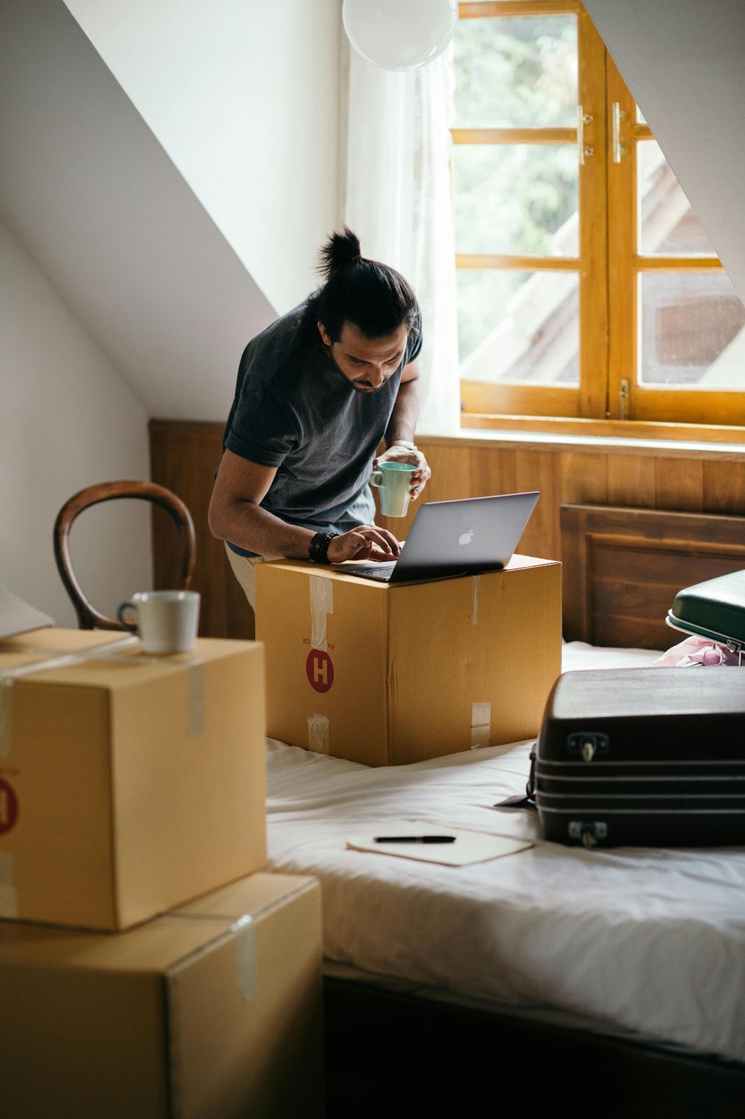 Man surrounded by moving boxes looking at laptop