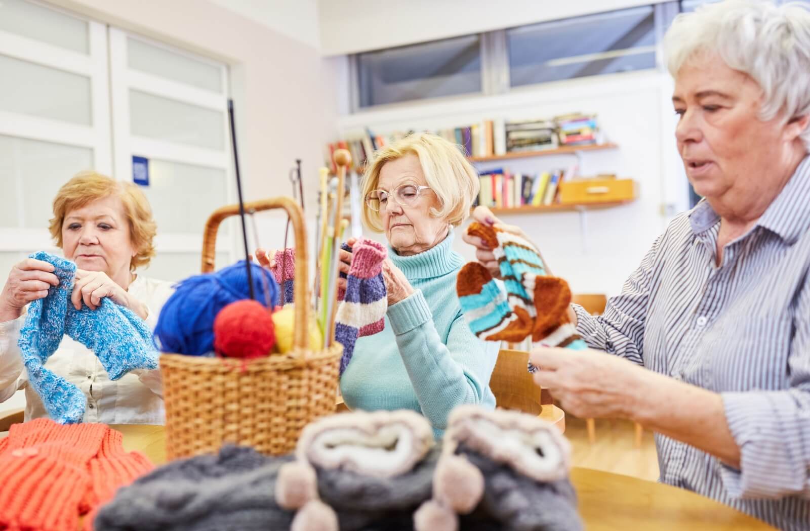 A group of seniors crochet together in a memory care community.