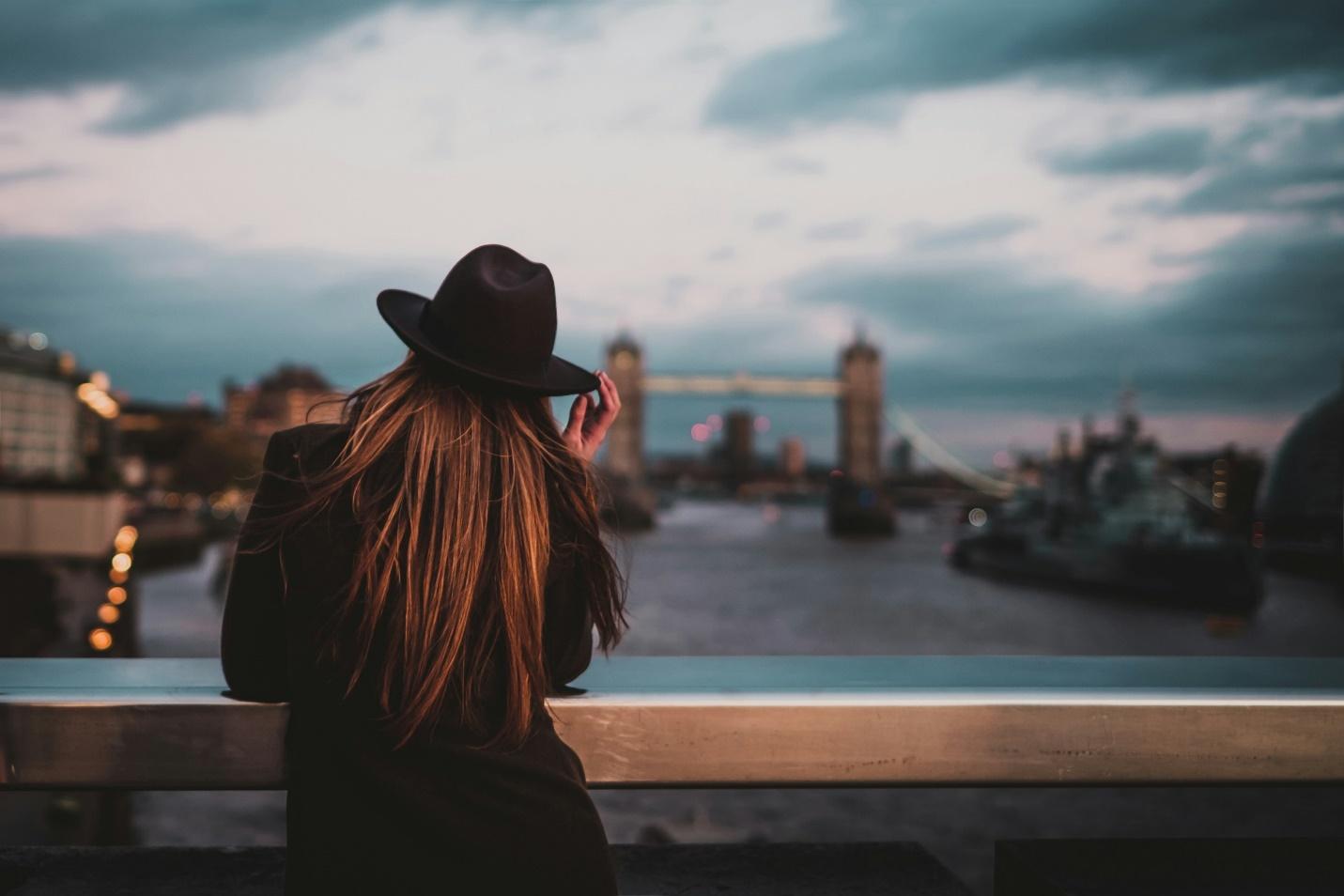 Lady in a hat looking from a bridge towards Tower Bridge in London