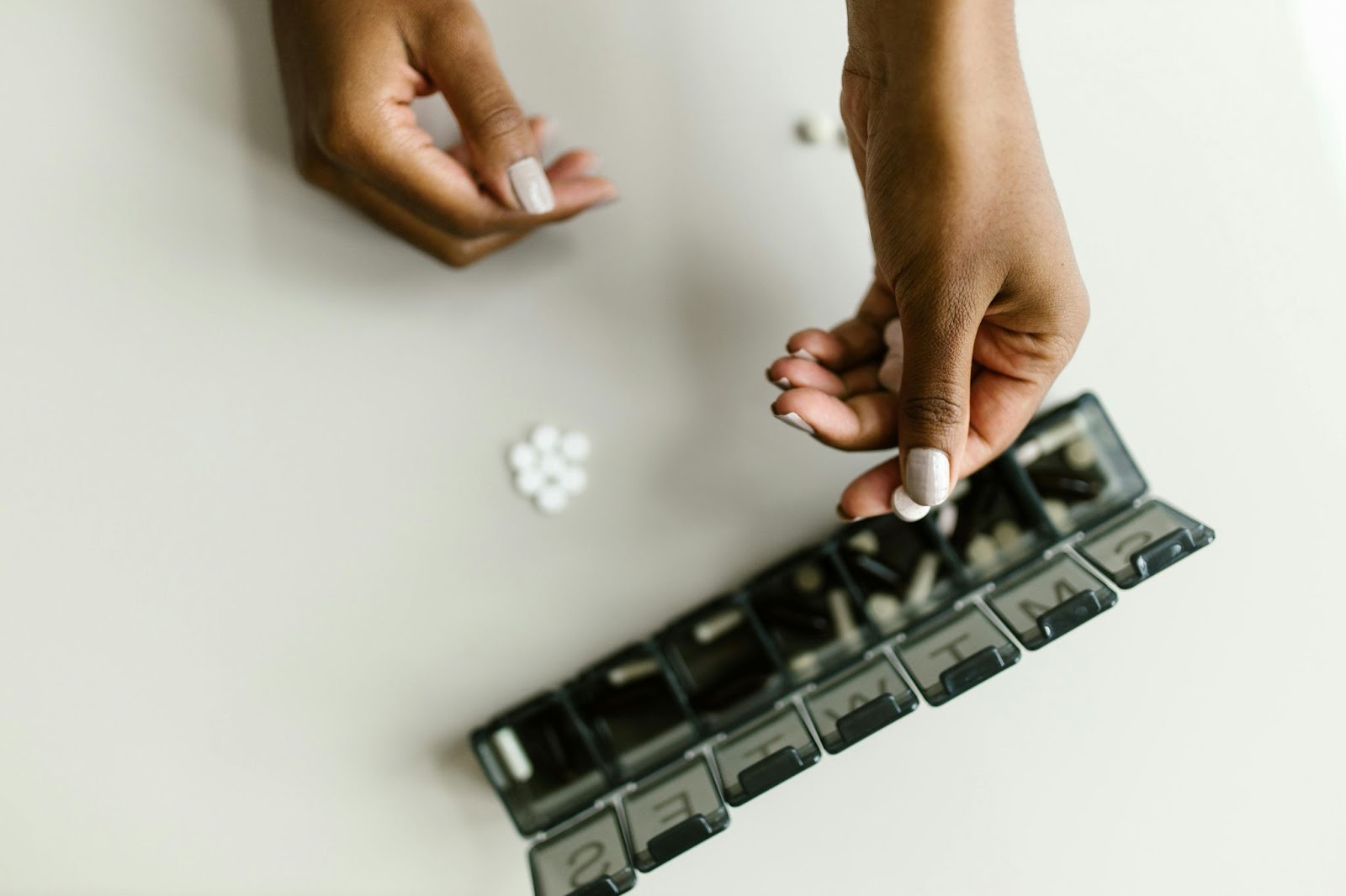 Person organizing daily medication in a weekly pill organizer