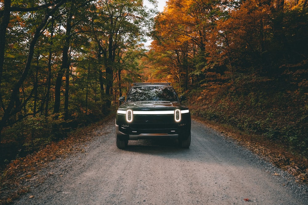 an Electric car on a dirt road surrounded by trees