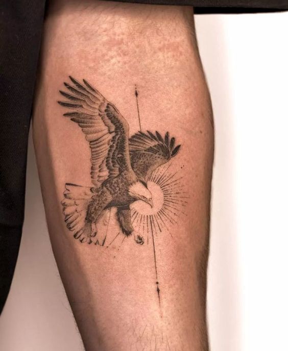 Tattoo of a detailed eagle in flight with a geometric sunburst design on a person's upper thigh.