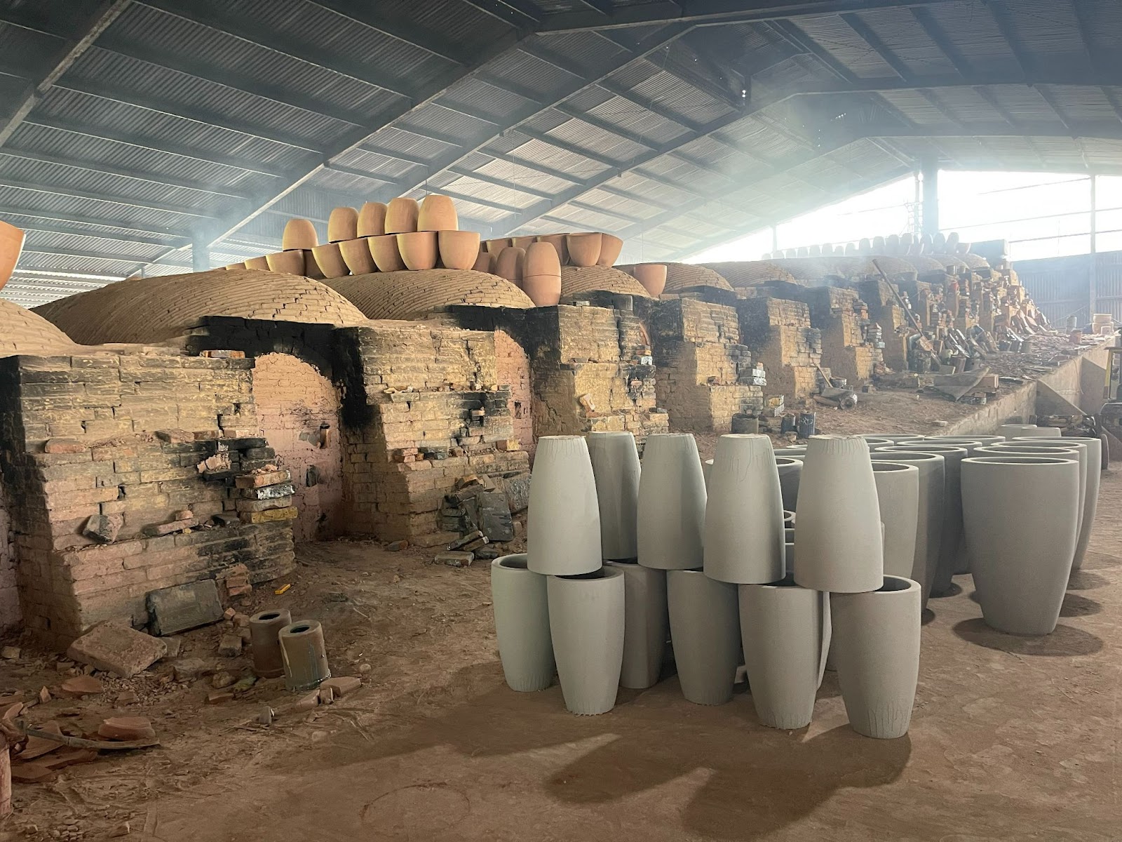 Image of unfired pottery standing next to a wood-fired dragon kiln