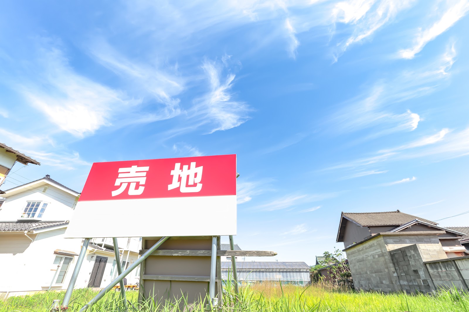 住宅街にある売地の看板と青空｜マイホームの土地選びや不動産購入前の現地確認イメージ