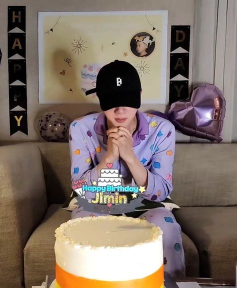 This is a picture of Jin in purple pajamas   and cake in front of him