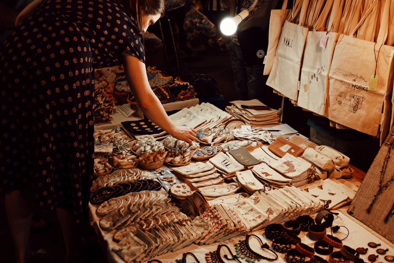 A woman examining a table filled with various items.