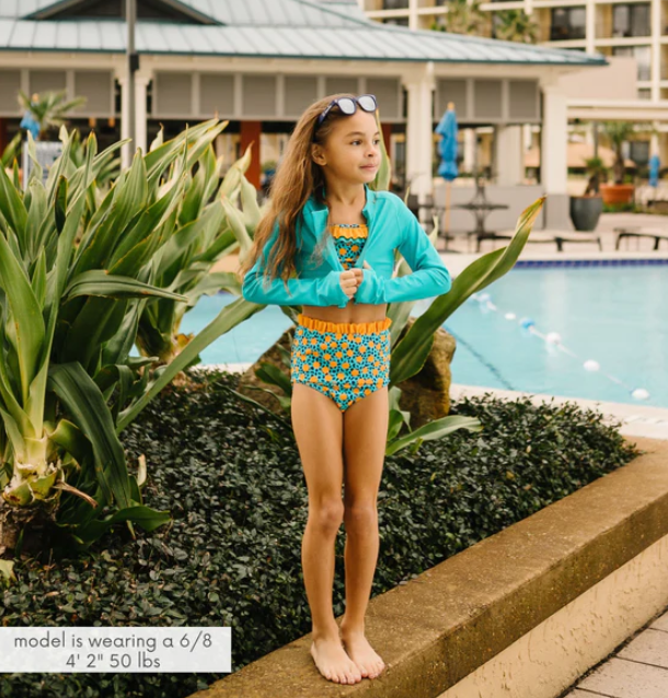 A girl in bright blue and yellow SwimZip two-piece set by the pool—Cute modest bathing suits for coverage and style