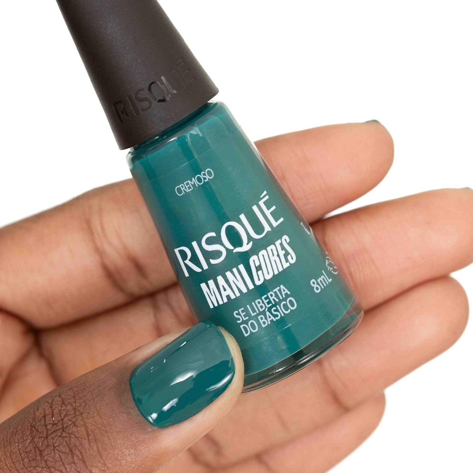 Uma mulher segura em sua mão o esmalte Se Liberta do Básico com as unhas pintadas de verde.