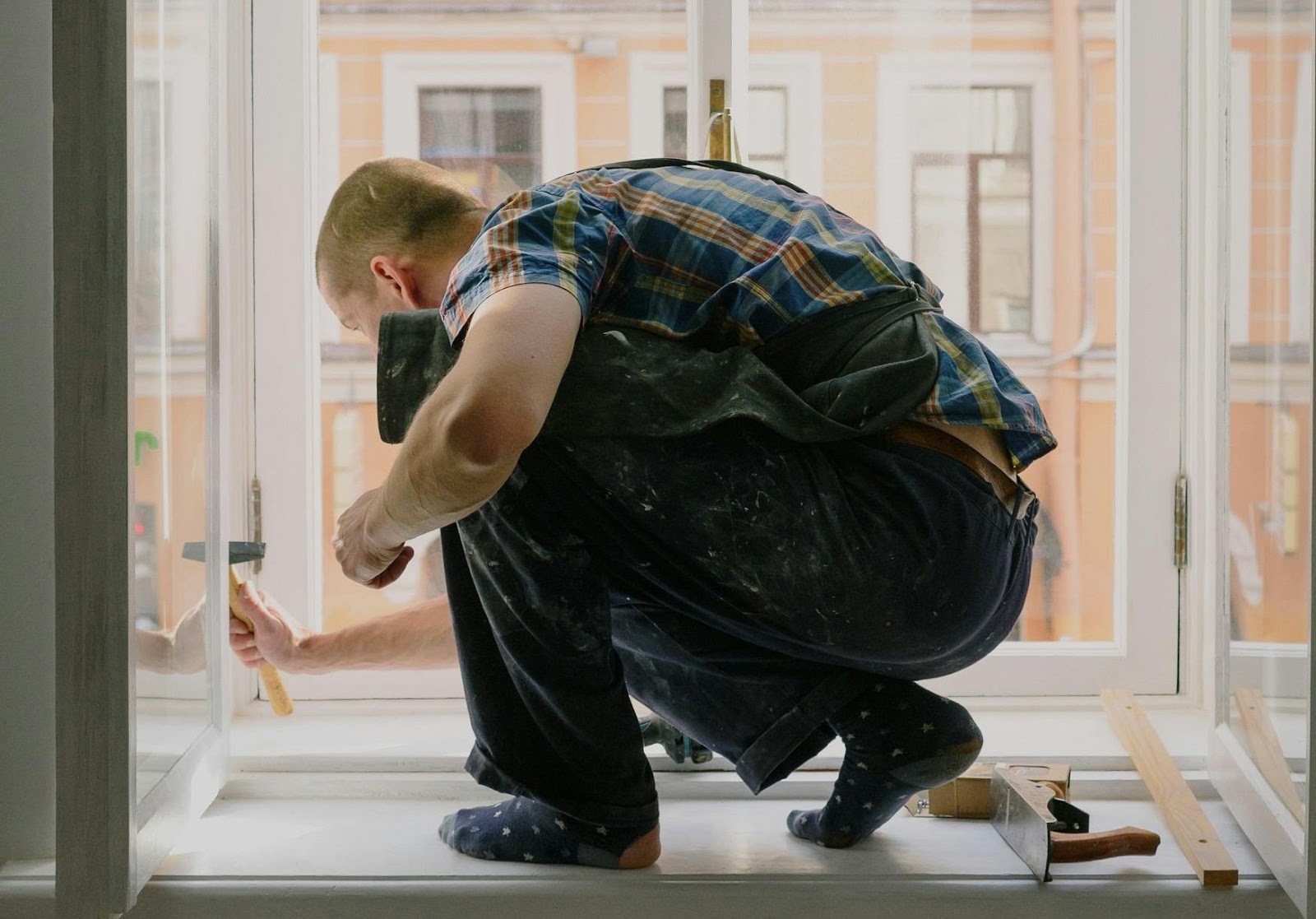 A man holding a hammer and fixing a window.