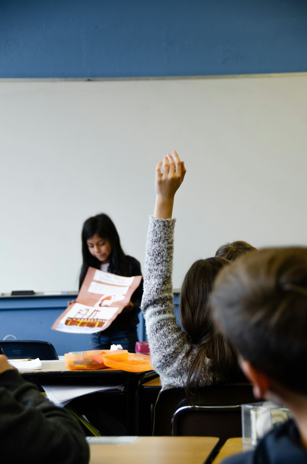 A student with her hand up during a classroom quiz