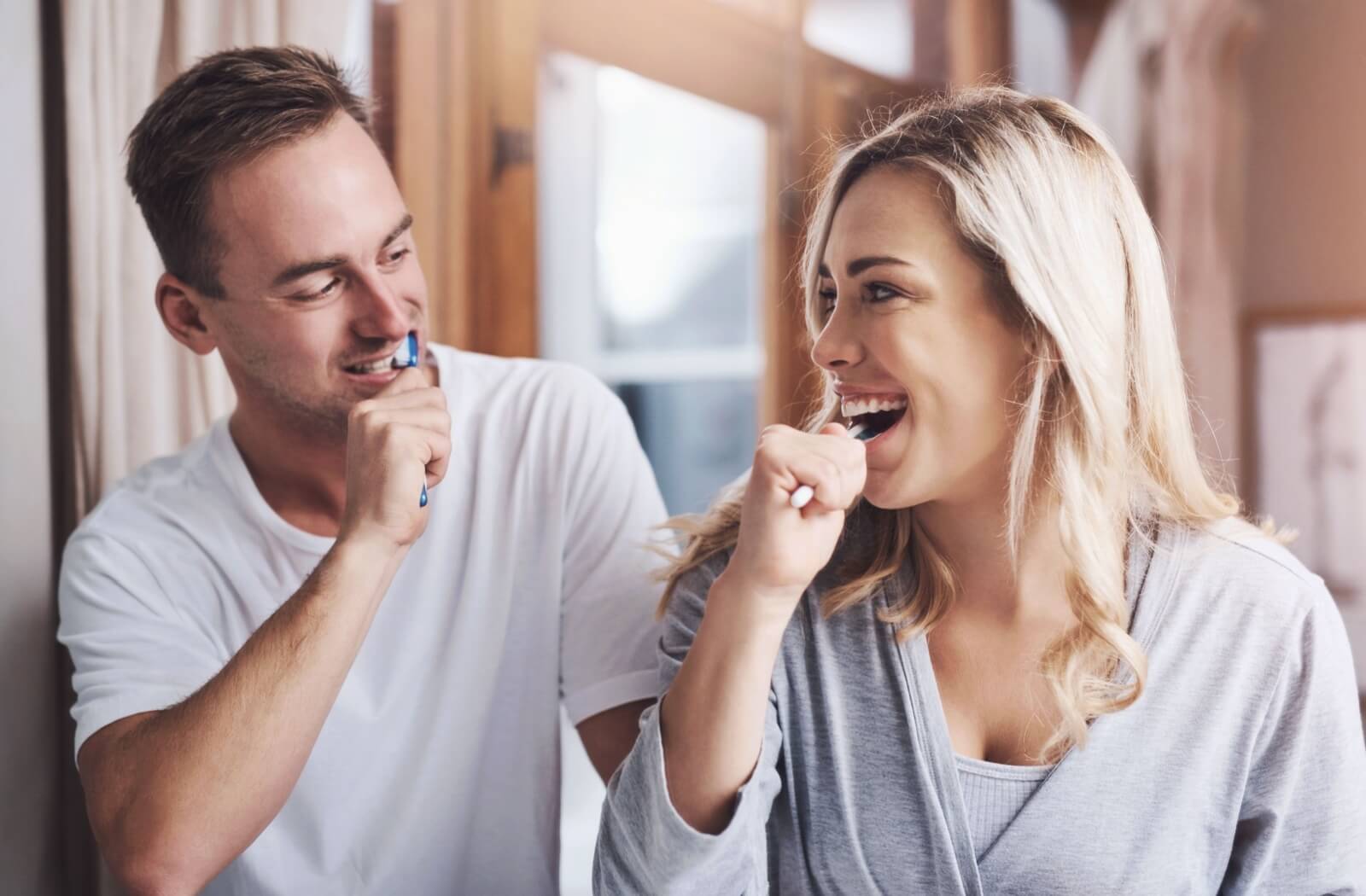 Family members next to each other brushing their teeth to help prevent gum disease.