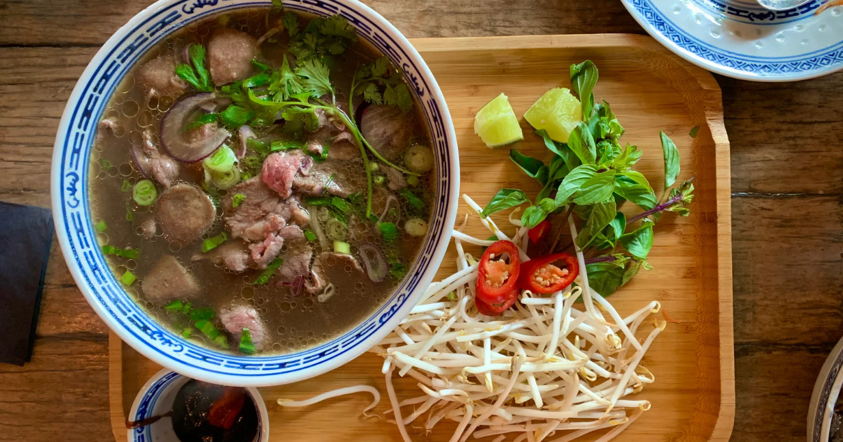 (kom rundvlees pho op een dienblad met pho toppings)