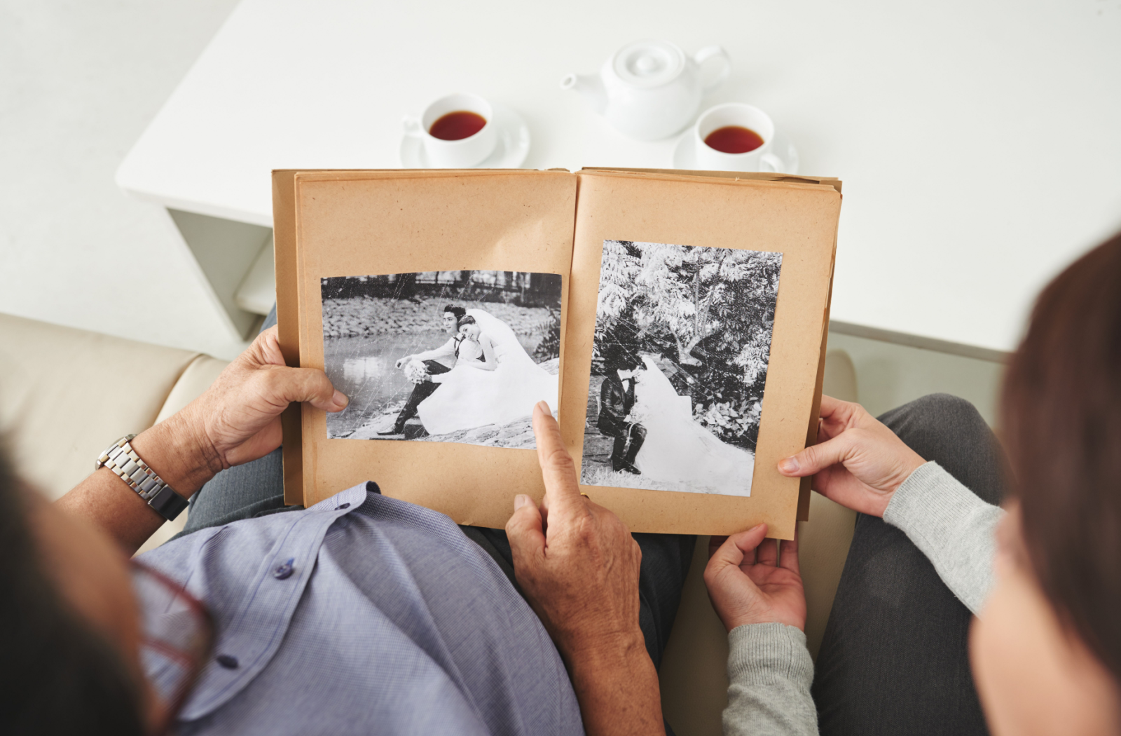 A senior and an adult sit together, looking at a black-and-white wedding album.