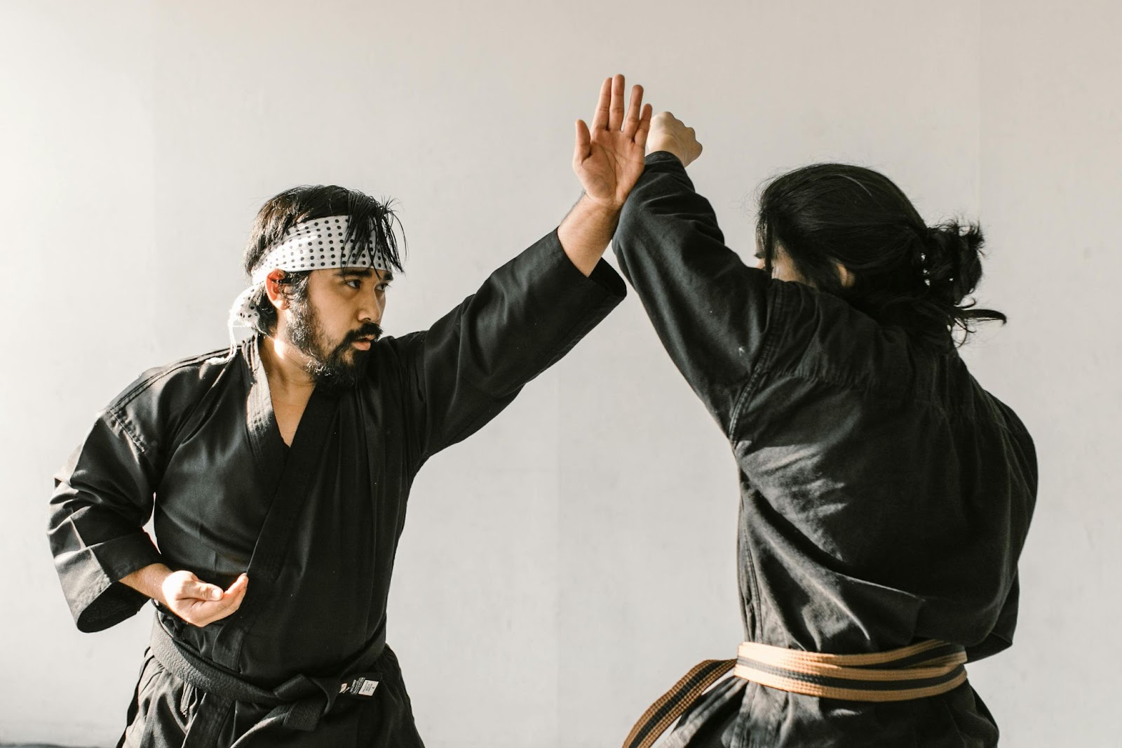 A martial arts instructor teaching a student how to block