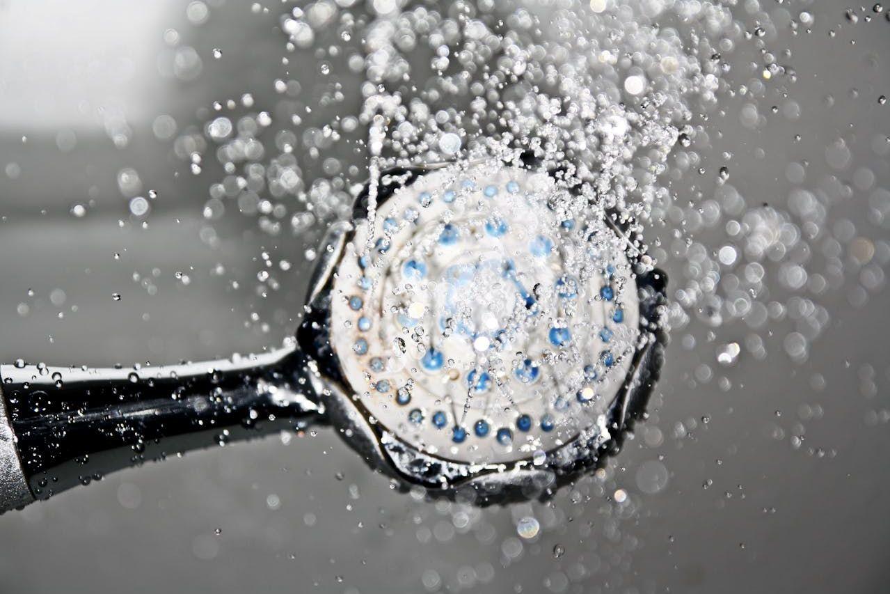 Black shower head turned on with water flowing