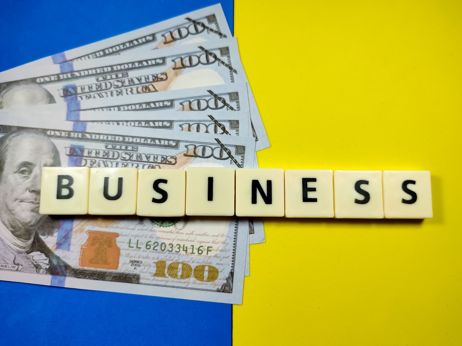 Dollar banknotes with the word 'BUSINESS' on a blue and yellow background.