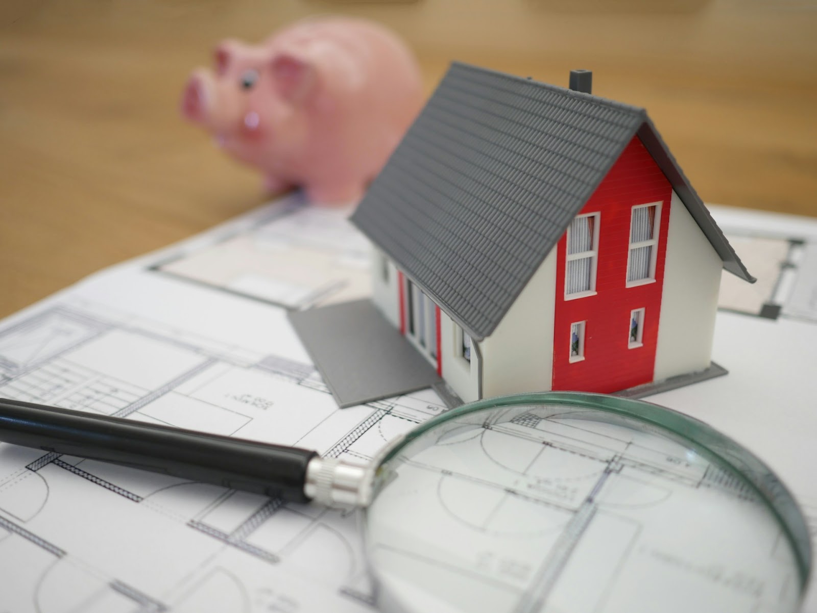 a magnifying glass, home model, and piggy bank