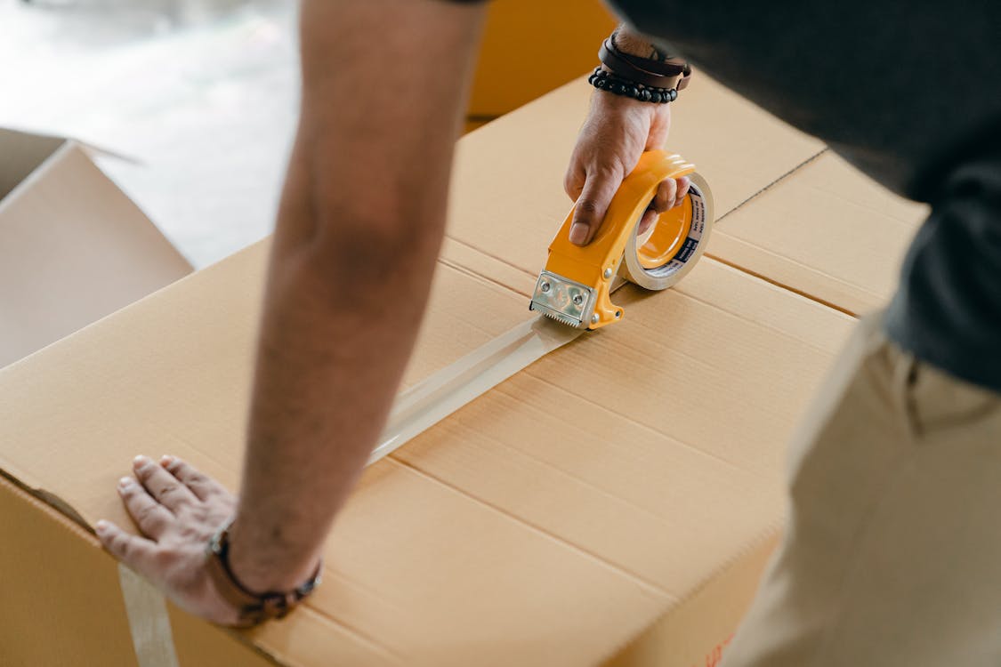 Man packing box with scotch tape