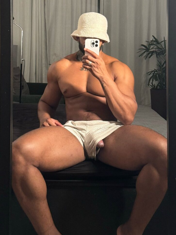 Lipe Scorpion taking an iphone mirror selfie with his half erect dick peeking out of his mesh white shorts wearing a furry brimmed hat