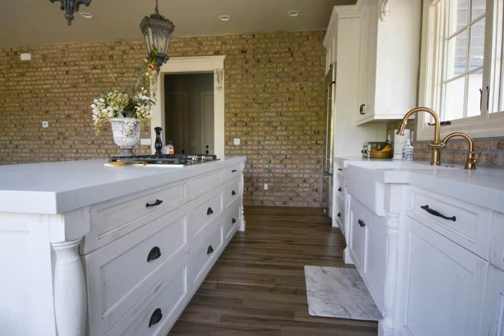 Built-in cooktop and a farmhouse sink paired with gooseneck faucets complete the kitchen.
