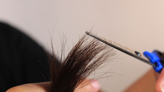 Close-up of dusting method for how to remove split ends yourself using precision scissors.