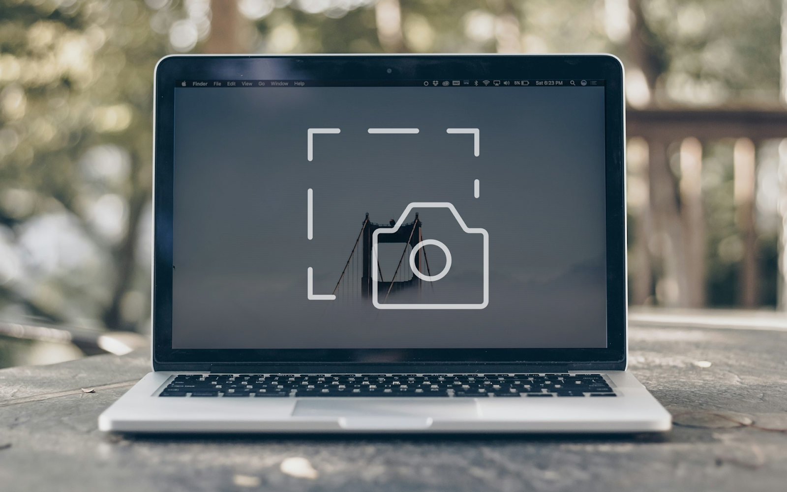 MacBook on a wooden surface with a screenshot icon on-screen