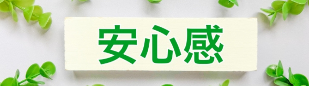 白いプレートに「安心感」と書かれた画像、緑の植物で囲まれたナチュラルで信頼感のあるデザイン