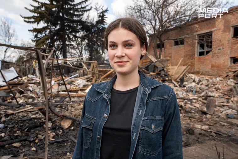 A person standing in front of a destroyed building

Description automatically generated