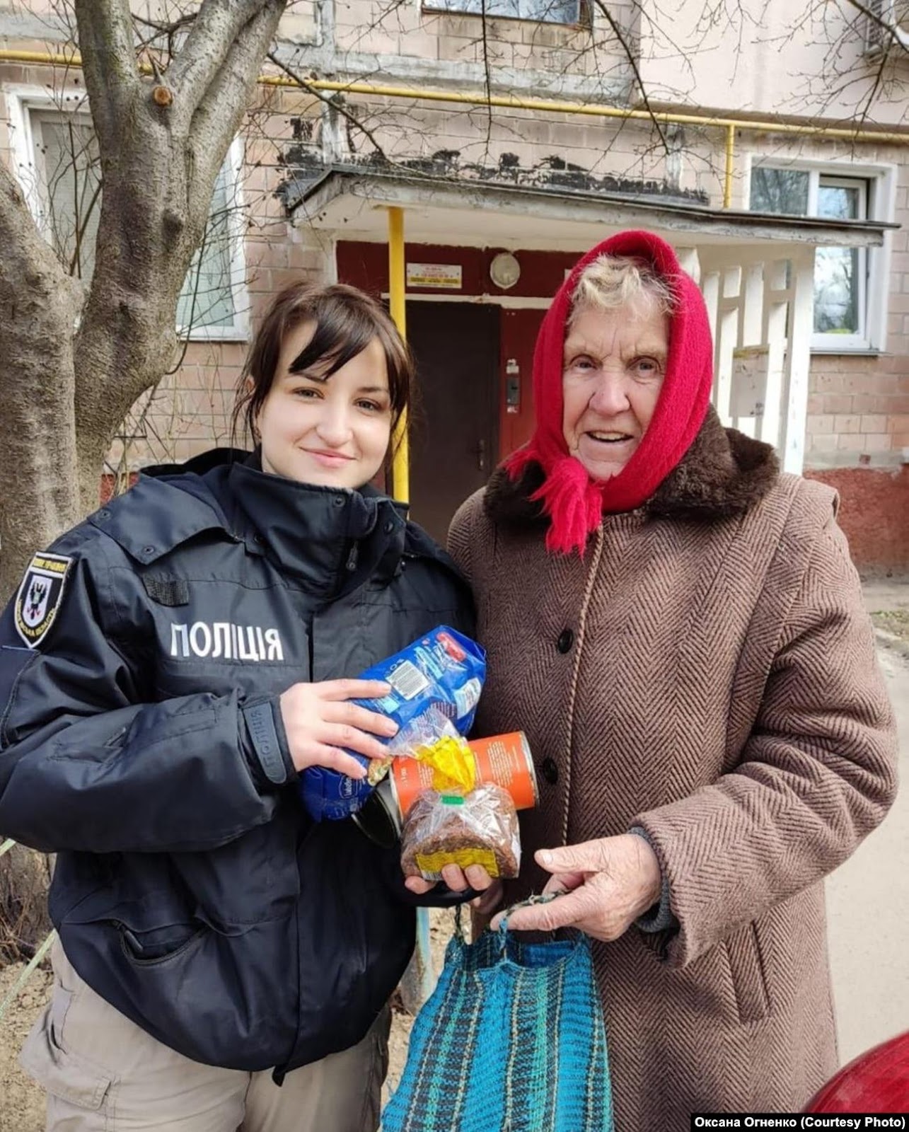 A person holding a bag of food and a person standing outside

Description automatically generated