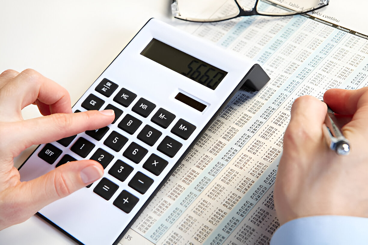 Person using a calculator and financial records, representing the comparison between single-entry and double-entry bookkeeping for businesses.