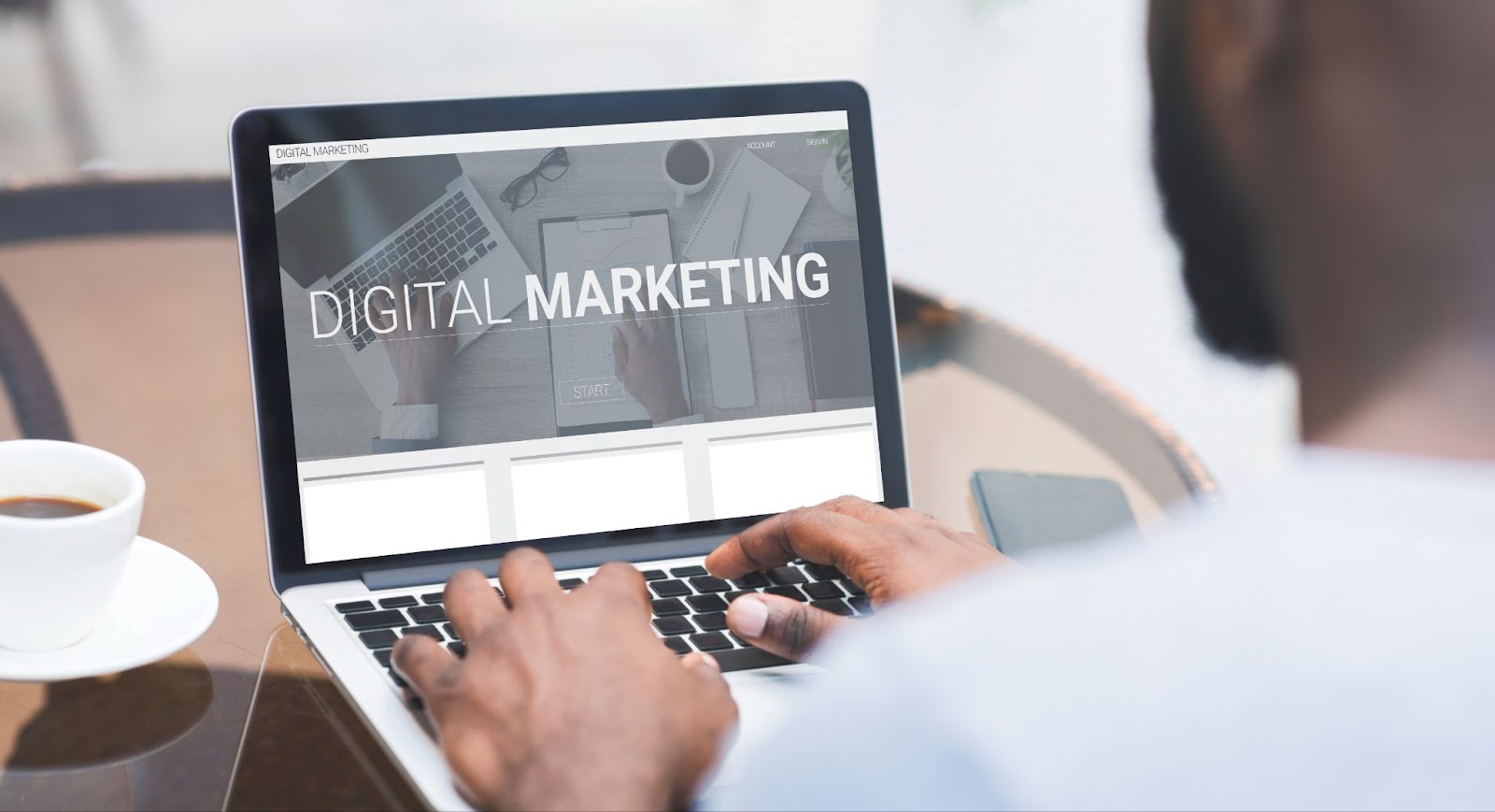 A view from behind a man using a laptop with a screen that says “digital marketing.”