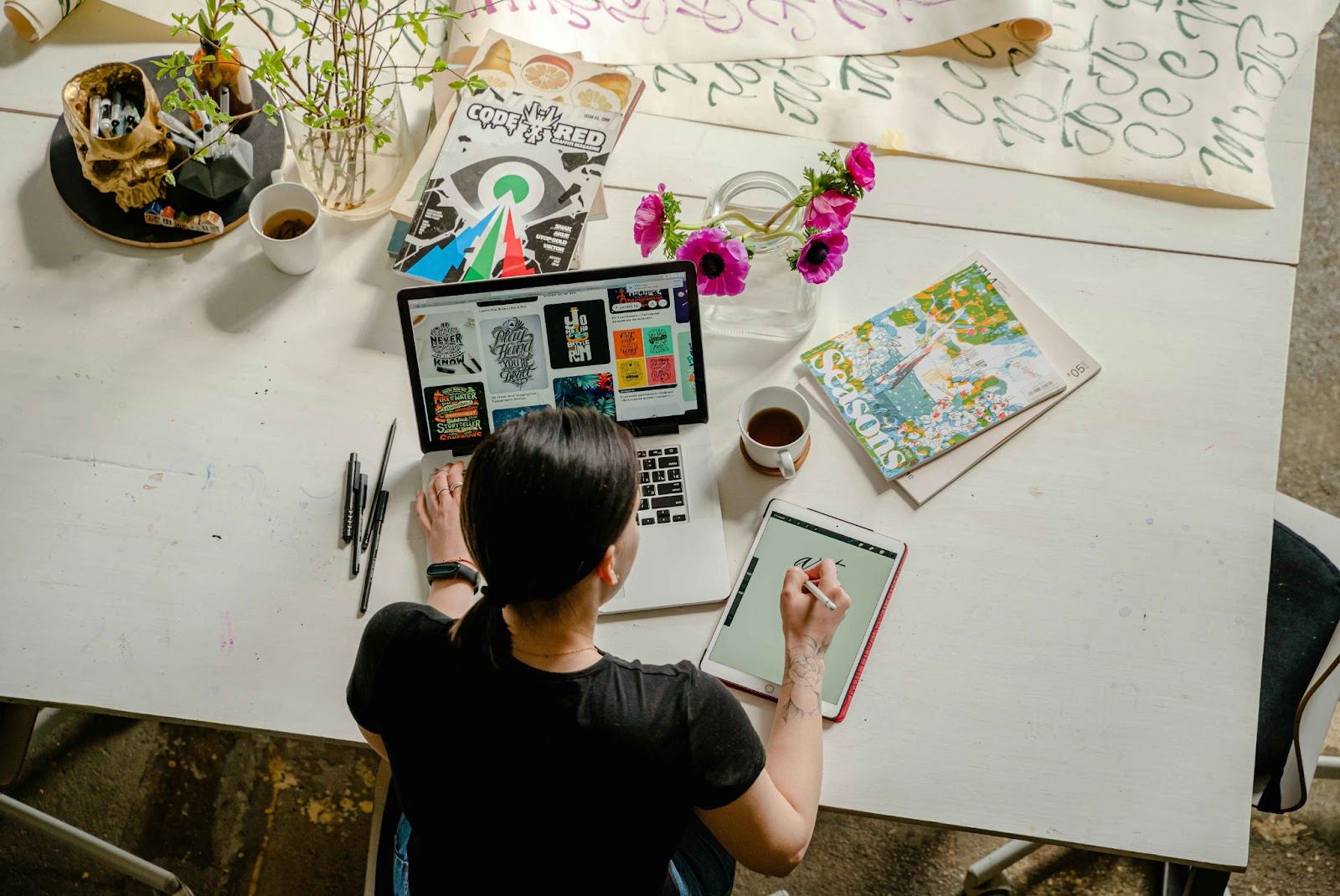 A person sitting at a desk, working on a laptop and a digital tablet