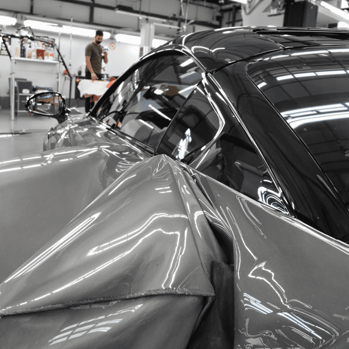 A luxury car being detailed in a bright, modern garage, highlighting its shiny exterior and pristine interior with high-end detailing products and tools.