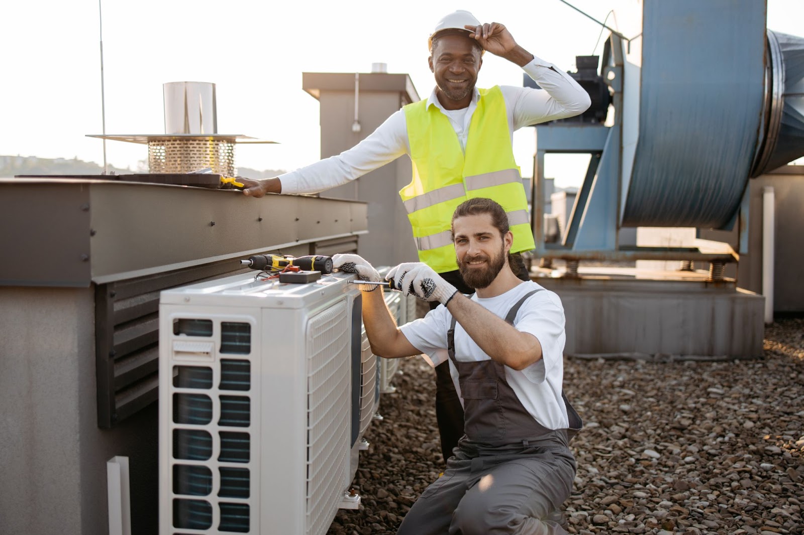 Repairmen on the roof fixing and improving an air conditioner, providing professional air conditioning repair services for optimal cooling performance.