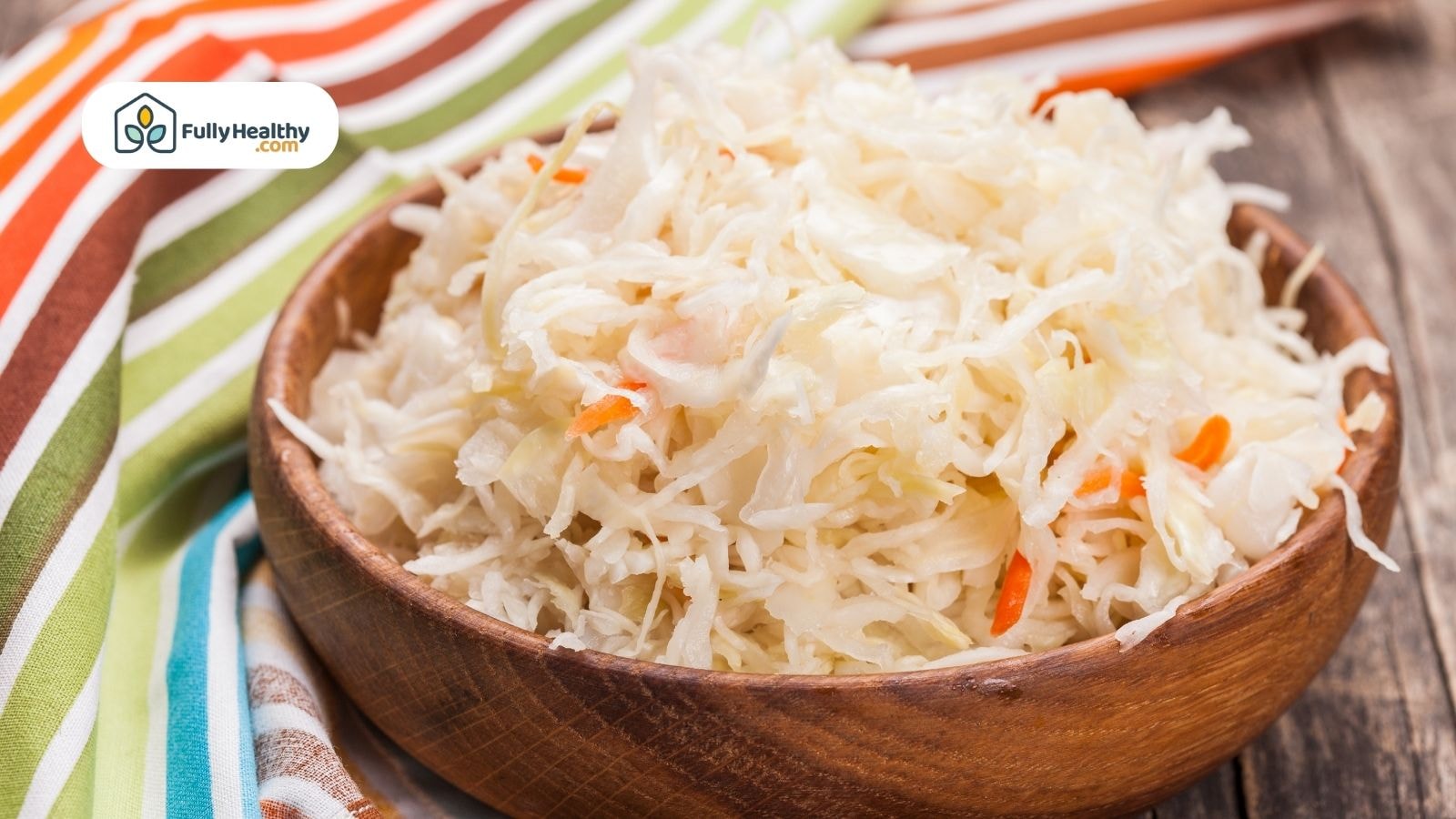 Bowl of sauerkraut on striped cloth with wooden background