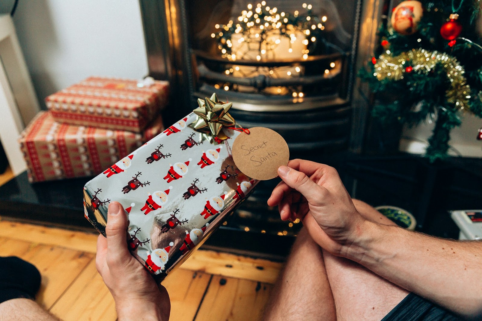 A person holding a present with a tag that says 'Secret Santa'