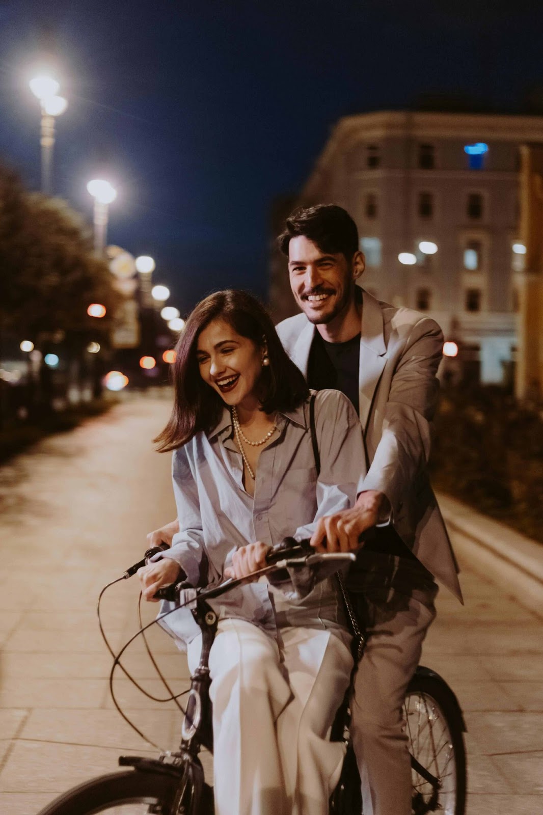 Smiling couple on a bicycle ride under the moonlight, perfect for pre-wedding shoot with props