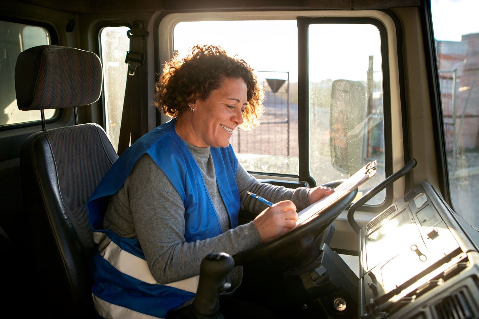 Mujer sonriente escribiendo en una guía de despacho representando la facilidad en la gestión y control de operaciones logísticas a través de un sistema de gestión de flotas TMS