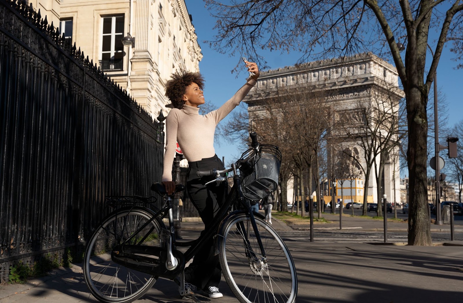 Une femme prend un selfie avec son vélo de location OneBike en face de l’Arc de Triomphe à Paris