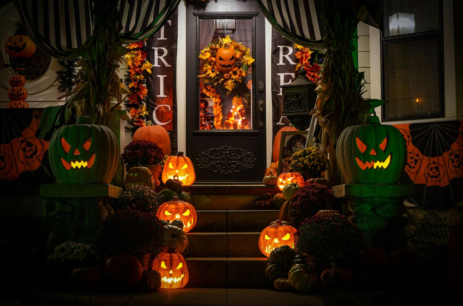 Front steps of a home at night with several illuminated jack-o-lanterns