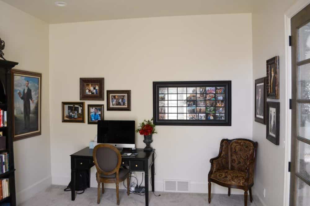 Home office with a dark wood desk, a patterned wingback chair, and framed artworks adorning the beige walls.