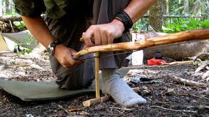 A man using a bow and drill method to light a fire as one of the techniques in  how to start a fire without matches or lighters