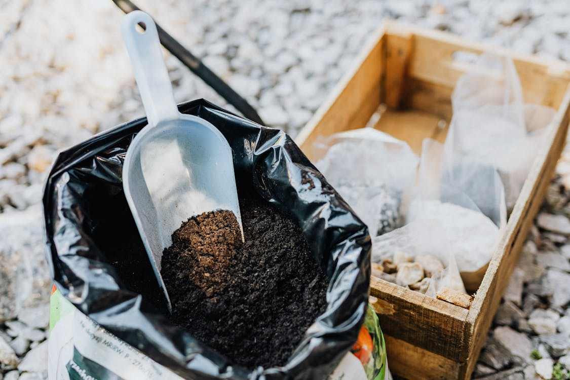 Bag of fertilized soil, partially opened to reveal dark, nutrient-rich contents.