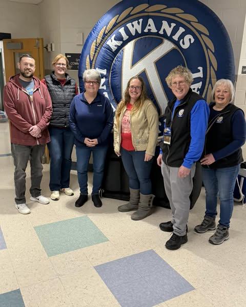 A group of people standing in front of a blue and white logo

Description automatically generated