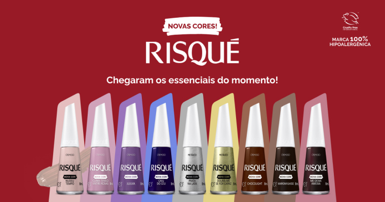 Imagem de oito esmaltes Risqué alinhados em uma mesa, cada um em uma cor diferente, incluindo tons agora disponíveis em novas cores. Fundo vermelho com texto destacando "Novas Cores!", "Risqué" e "Chegaram os essenciais do momento!".
