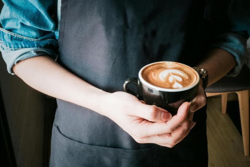 "A serene image of a woman gently holding a warm mug of cappuccino, her hands wrapped around the cup as steam rises softly. The cappuccino's frothy top is adorned with delicate latte art, while the woman gazes down, savoring the moment. The scene exudes warmth and comfort, emphasizing the simple pleasure of enjoying a well-crafted coffee."







