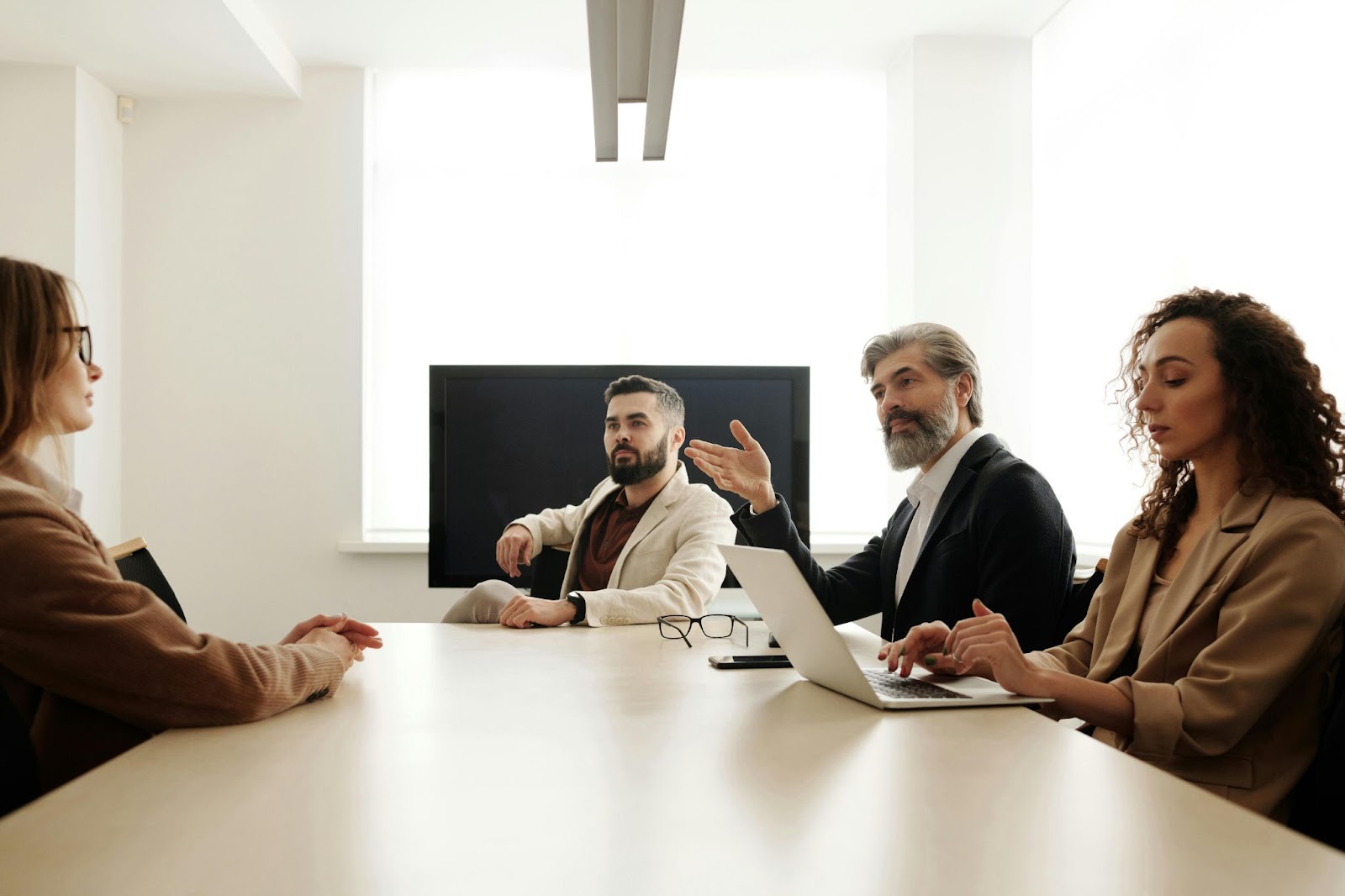 Four people are seated at a conference table.