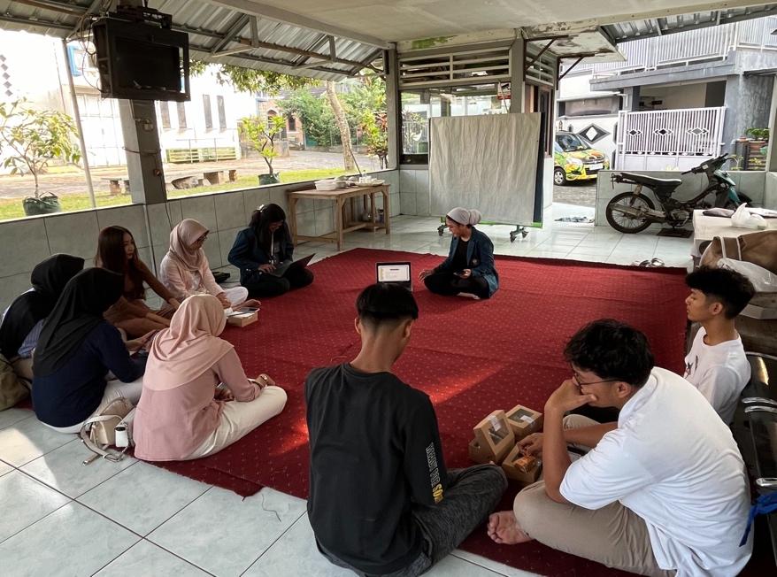 A group of people sitting on a red carpet

Description automatically generated