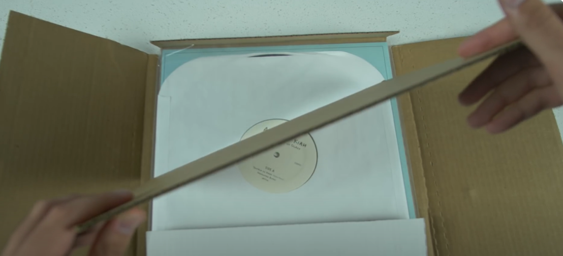 Layering a vinyl record with protective cardboard inside a shipping box